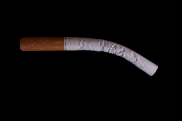 A bent cigarette on a black background. The concept of smoking harm, impotence