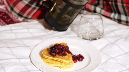 Breakfast in bed. Heart shape pancakes with jam. Pouring tea. Romantic surprise meal. 