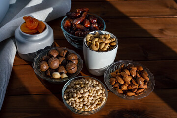 Composition of different delicious nuts and dried fruit under natural sunlight on wooden table