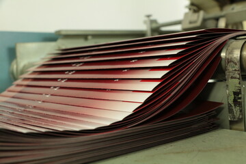 Fototapeta na wymiar printing press brochure folding machine, the moment of folding. selective focus is used.