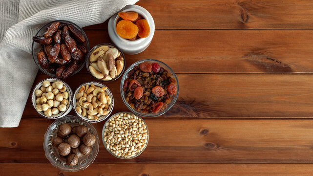 Different delicious nuts and dried fruit on wooden table. Healthy food and snack. Brazilian and pine nuts, hazelnuts, macadamia, cashews, dates, dried apricots and raisins