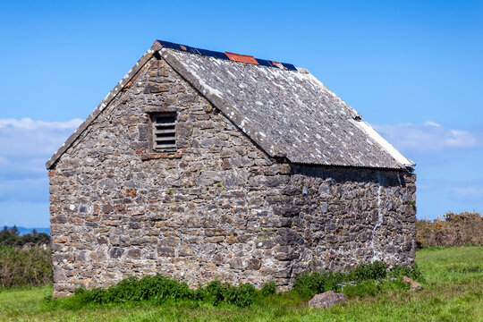 Stone barn shed in a summer pasture field on Caldey Island of the coast of Tenby Pembrokeshire South Wales, stock photo image