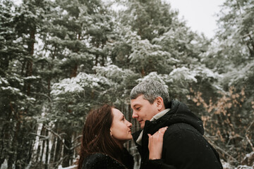 Adult man and woman on the background of a winter snow-covered pine forest