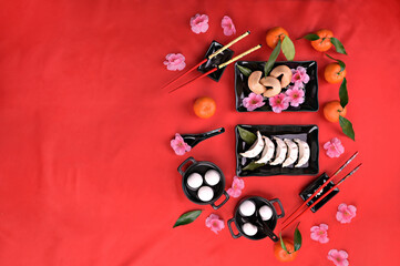 Flat lay Chinese new year food and drink still life. Food and drinks, steamed dumpling, Tangyuan rice balls, fortune cookies on black plate and red background. High quality photo. Copy space.