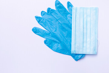 A pair of blue medical latex gloves and a medical mask against white background with side space. Means of protection during the spread of the virus.