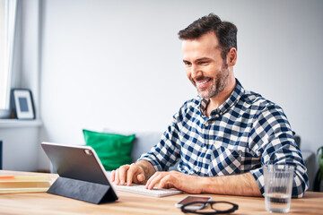 Smiling man working from home using digital tablet