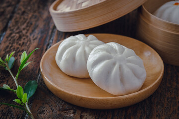 Steamed pork buns on wooden plate, Chinese dim sum .