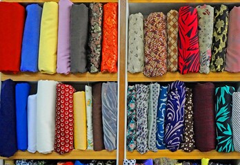 Many rolls of silk fabric of different colors for designers, sewing clothes, in the workshop, in the store on the shelf.