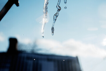 Icicle with water drops on a background of blue sky
