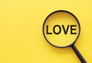 The word LOVE is written on a magnifying glass on a yellow background.