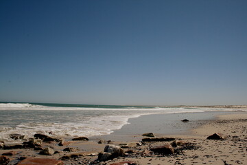Moody ocean on a sunny day. Rocks and sand on the beach