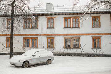 Winter in an ordinary Russian city.
A simple Russian car stands under the snow near a wooden house...