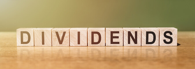 DIVIDENDS word written on wooden blocks on wooden table. Concept for your design.