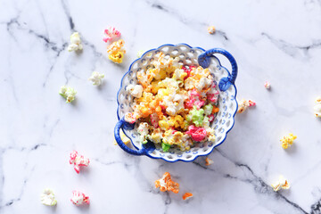 Fototapeta na wymiar colorful popcorn in a bowl on tiles background top down 
