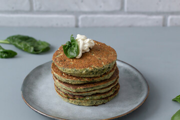 Spinach and banana pancakes with fresh leaves on a gray plate on a gray background. Healthy food concept. Horizontal orientation.