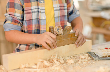 Fototapeta na wymiar Close up kids hands planing wood in a workshop