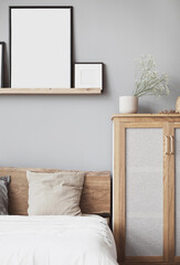 Blank picture frame mockup on gray wall. White bedroom design. View of modern scandinavian style interior with bed. Home staging and minimalism concept