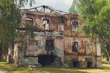 the remains of a derelict abandoned stone house covered in moss and overgrown with trees in a...