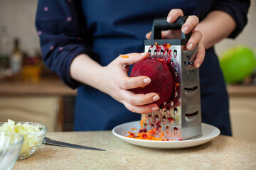 Young woman rubs beets. Cooking Ukrainian borscht step by step
