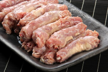 Raw Chicken neck skinless on a clay plate, Black bamboo napkin in the background