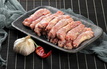 Raw Chicken neck skinless on a clay plate, Black bamboo napkin in the background