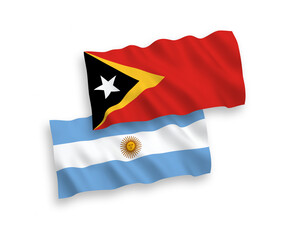 National vector fabric wave flags of East Timor and Argentina isolated on white background. 1 to 2 proportion.