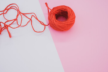 Closeup shot of a bright red woolen yarn on a purple and white background