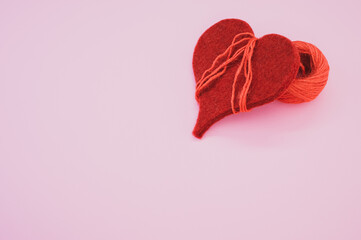 Closeup shot of a bright red yarn with threads wrapped around a red heart-shaped textile