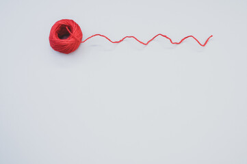 Closeup shot of bright red woolen yarn on a gray background