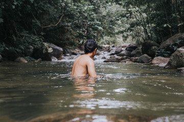 Fototapeta na wymiar A male traveler in the rain forest pool stream or waterfall.Healthy and active lifestyle.Camping and hiking.
