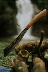 Special designated Asian knife called " Parang" sticked on the log wood with waterfall background.Camping knife and safety.