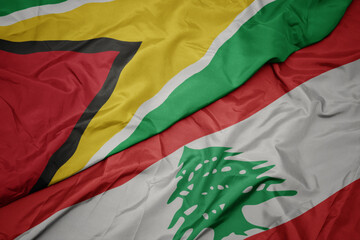 waving colorful flag of lebanon and national flag of guyana.