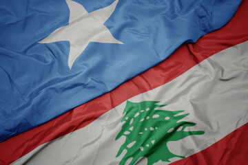 waving colorful flag of lebanon and national flag of somalia.