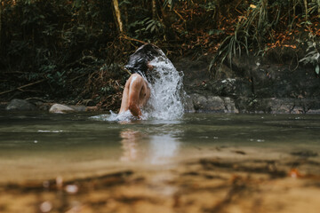 A male traveler in the rain forest pool stream or waterfall.View from behind.Healthy and active lifestyle.Camping and hiking.Soft focused due to slow shutter shot.