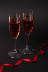 Two Champagne glasses on the black background with a red ribbon. Composition for Valentine's day