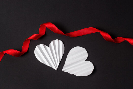 Valentine's day flat lay with copy space. White hearts with red ribbon on the black background. Image for greeting cards. Valentine's day concept	