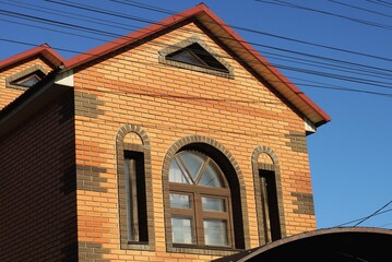 windows on brown brick attic wall against the blue sky