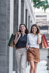 Young shopaholic friends women friends walking and carry shopping bags in the street city with happy and smiling.