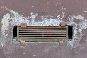 Old air vent in the wall. Metal grill. White salt, plaster.