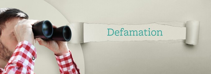 Defamation. Man (lawyer) observing with binoculars. Focus on text/word on a torn paper.