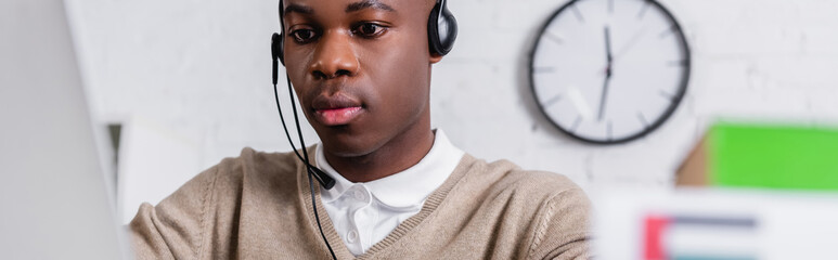 serious african american interpreter in headset working in translation agency, banner