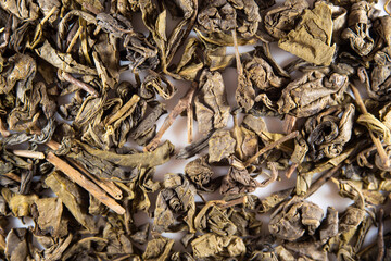 Green large-leaf tea as a background. Texture of dry green tea leaves. Dark background. Macro mode. black leaf tea close up