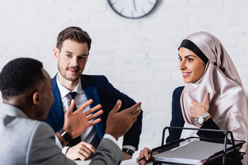 african american businessman gesturing during discussion with smiling multicultural business...