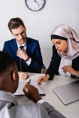 arabian businesswoman pointing with finger at contract during meeting with african american partner...