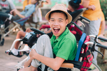 Asian disabled child on wheelchair is playing, learning and exercise in the outdoor park with friends and teacher, Lifestyle of children in the special education school, Happy disability kid concept.