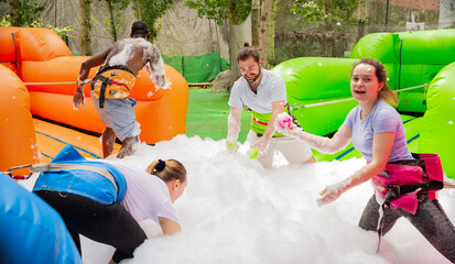 Game of funny friends in soap suds on an inflatable trampoline. High quality photo