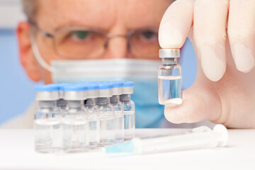 Fototapeta premium Doctor or scientist holding a vial with vaccine against covid-19 or influenza in his hand