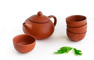 Terracotta teapot and cups on white background