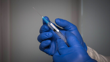 Flu shot in a syringe, the doctor holds a syringe with covid-19 vaccine