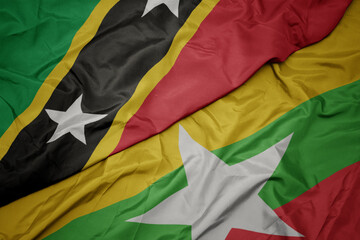 waving colorful flag of myanmar and national flag of saint kitts and nevis.